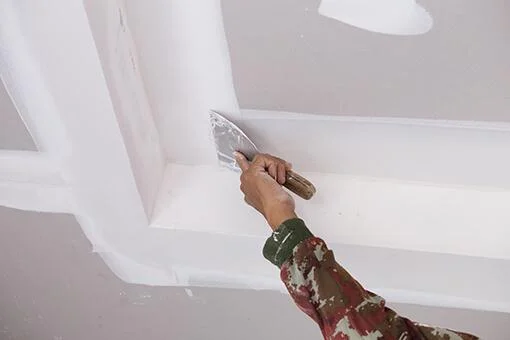 main-ouvrier-utilisant-joints-plafond-platre-gypse Finition sur plafond placo, ATL rénovation Arras